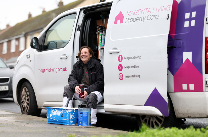 Colleague taking a break beside a Magenta Living Property Care van with paint tubs on the ground.