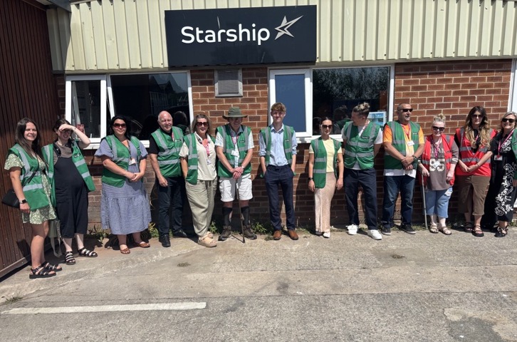 Members of the Magenta Customer and Communities Committee and Magenta colleagues stand outside Starship's manufacturing facility in Birkenhead during a development day visit. The group are wearing high-visibility visitor vests as they learn more about modern methods of construction and the delivery of sustainable homes.