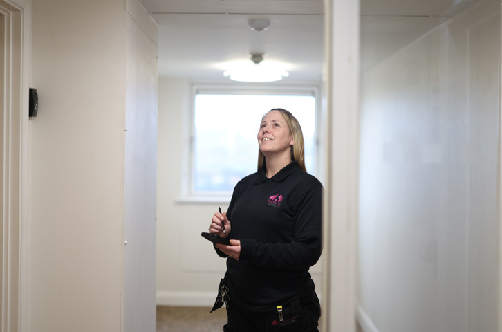 Colleague carrying out a property inspection in a hallway using a handheld device.