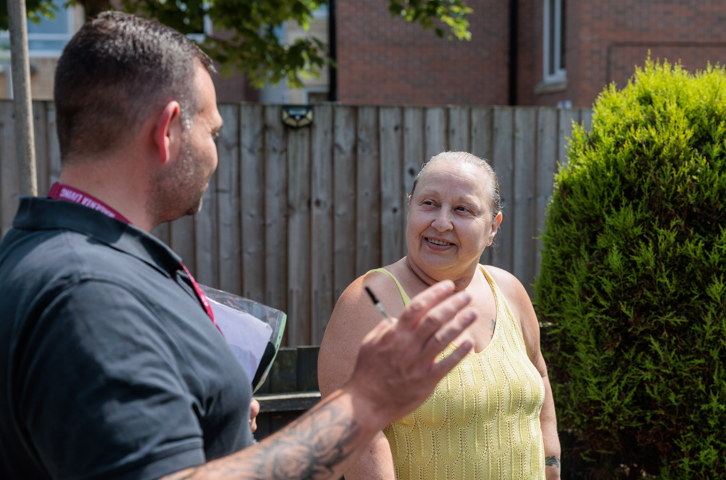 A customer and Magenta colleague talking outside a home in a neighbourhood.