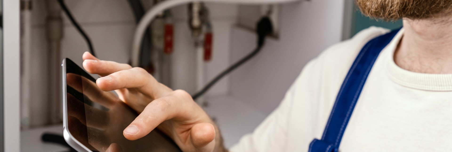 Technician inspecting a household boiler and recording information on a tablet.
