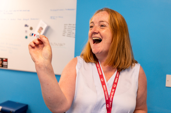 Colleague holding up a slip of paper showing a randomly drawn World Cup country for Magenta Living's Score Your Decor competition.