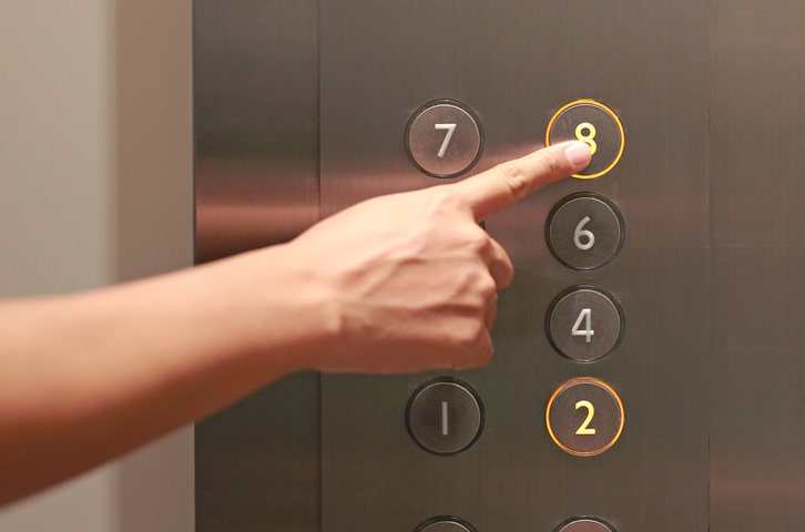 Hand pressing the button for floor eight inside a lift control panel.