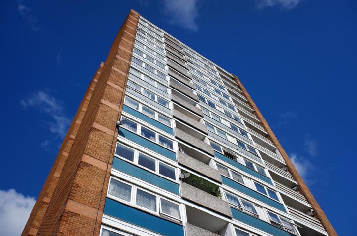 Low-angle view of a high-rise residential apartment block against a blue sky