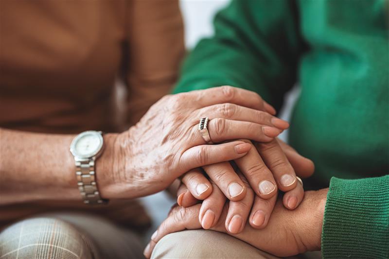 Close-up of two pairs of hands gently held together, showing support and reassurance.
