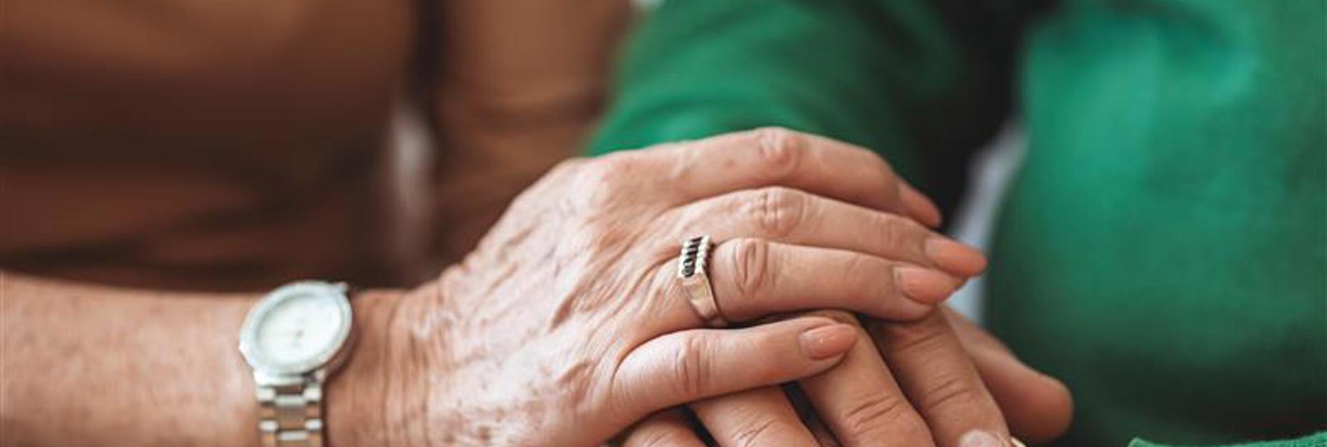 Close-up of two pairs of hands gently held together, showing support and reassurance.