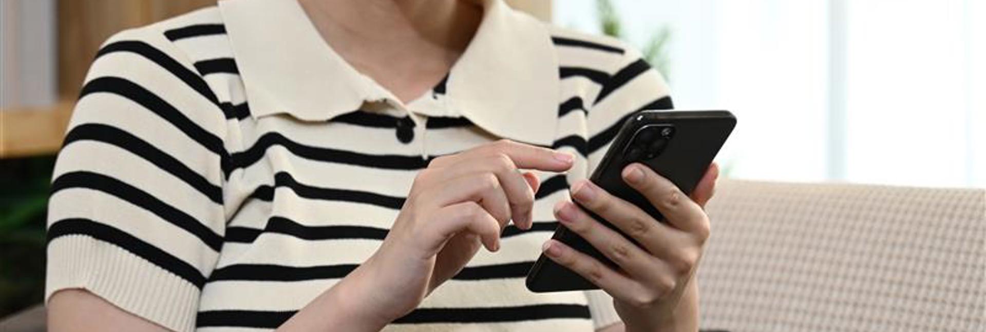 Person sat on a sofa scrolling through their phone.