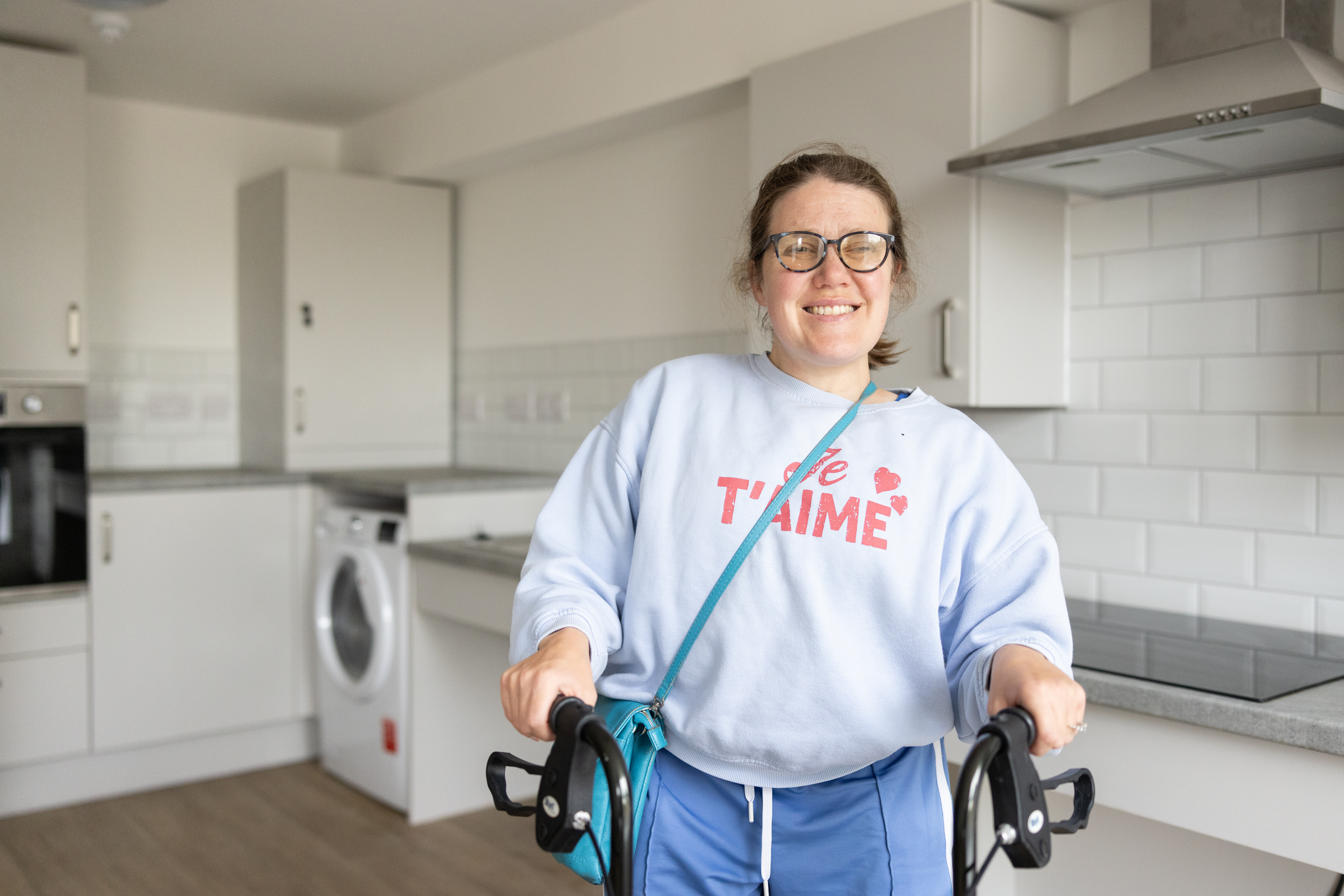 Person smiling in a bright, modern kitchen.