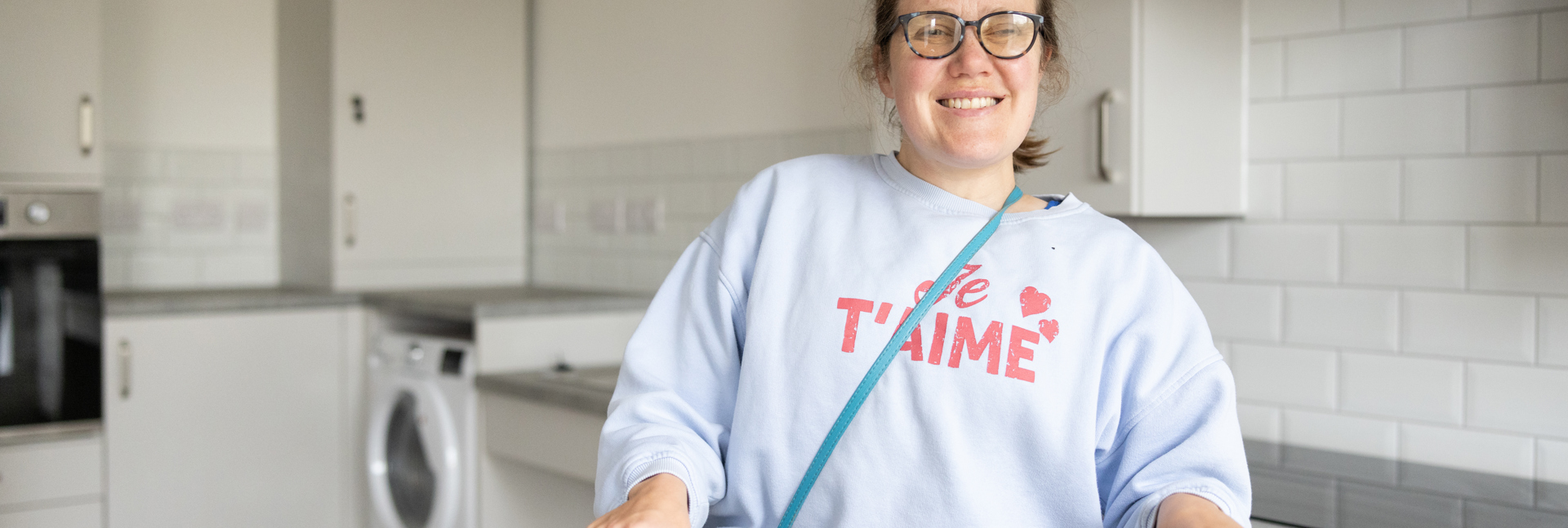 Person smiling in a bright, modern kitchen.
