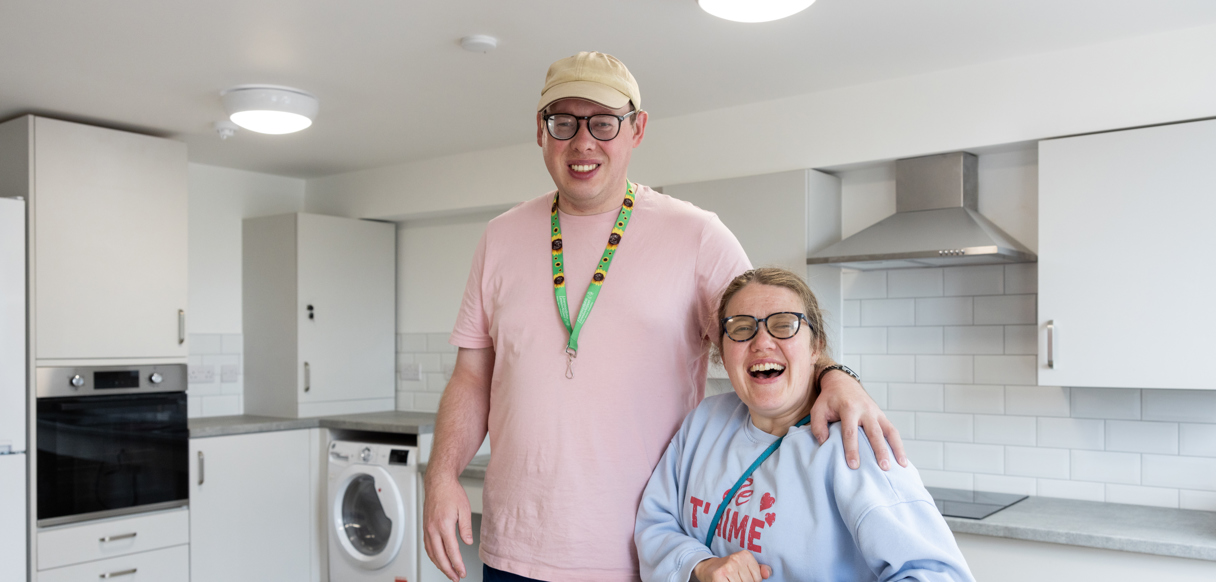 Two people smiling together in a bright, modern kitchen.