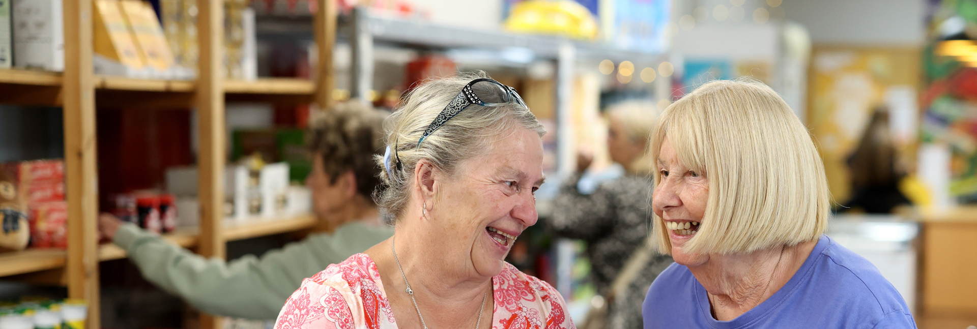 Two people holding mugs chat together in a welcoming community space.
