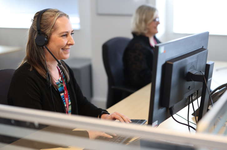 Magenta Living colleague speaking with a customer using a headset at a computer.
