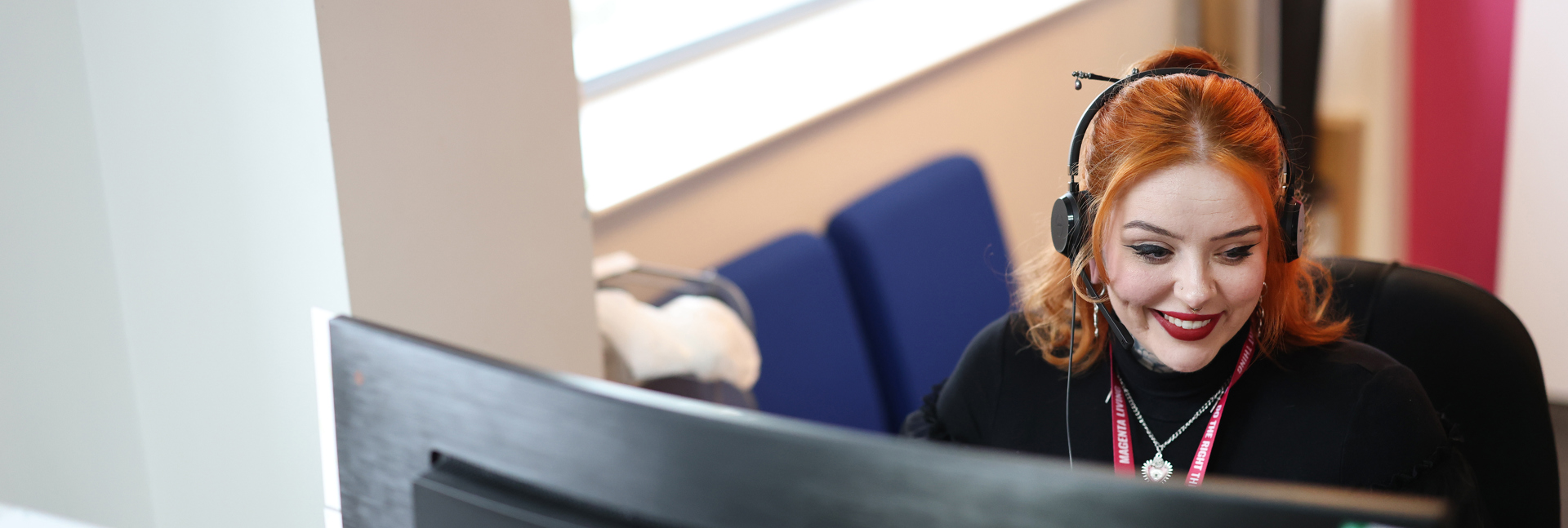 Colleague wearing a headset while working at a computer in a bright office.