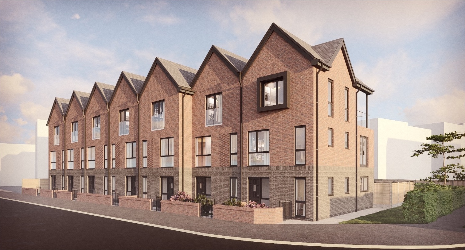 New terraced brick homes with tall windows and small planted areas at the front.