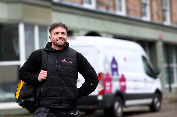 Colleague carrying a work bag in front of a Magenta Living repairs van.