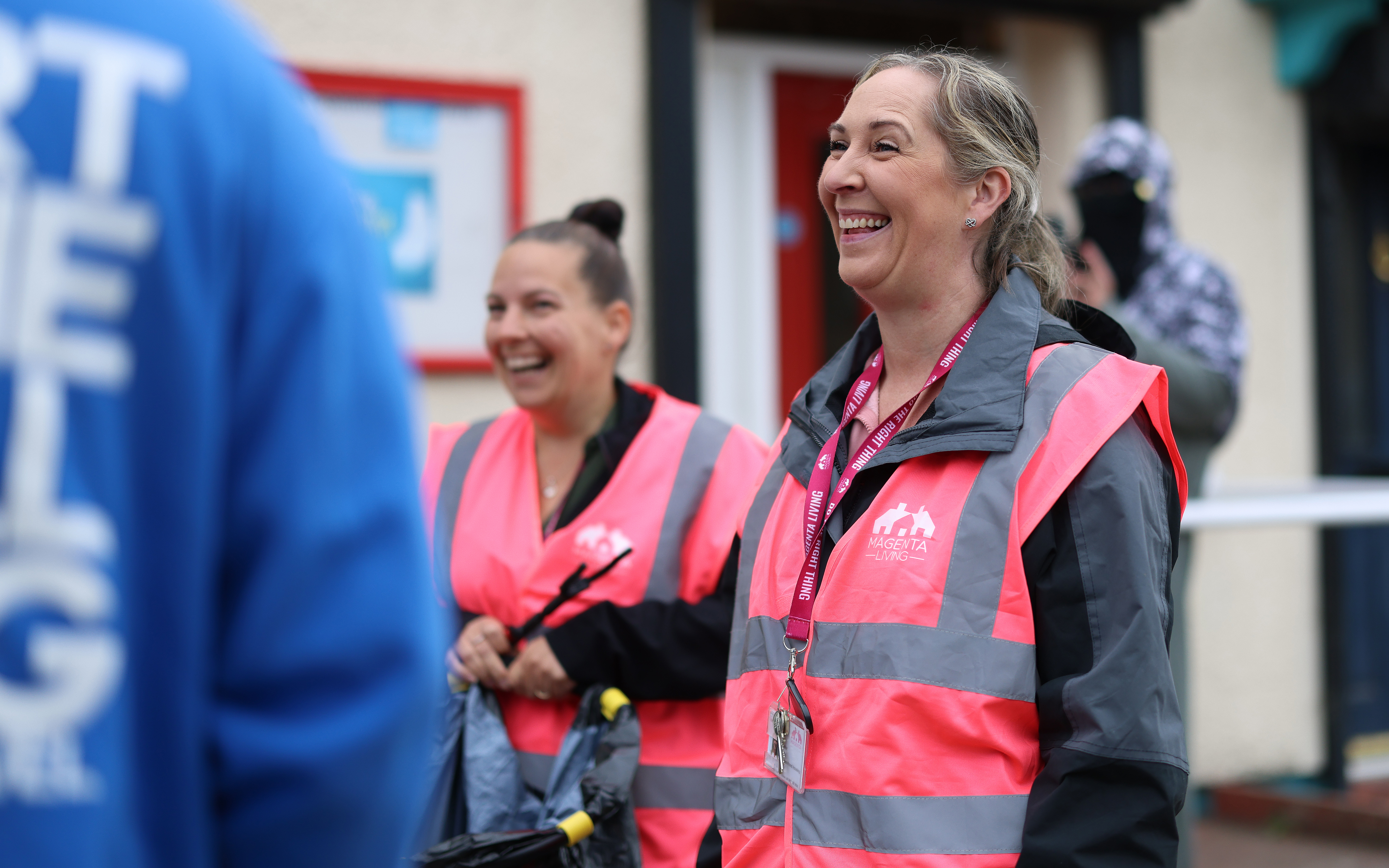 Community volunteers wearing bright pink safety vests during an outdoor clean‑up activity.