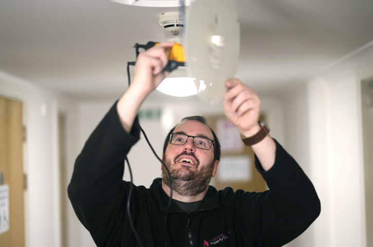 Colleague carrying out a fire alarm testing in a hallway.