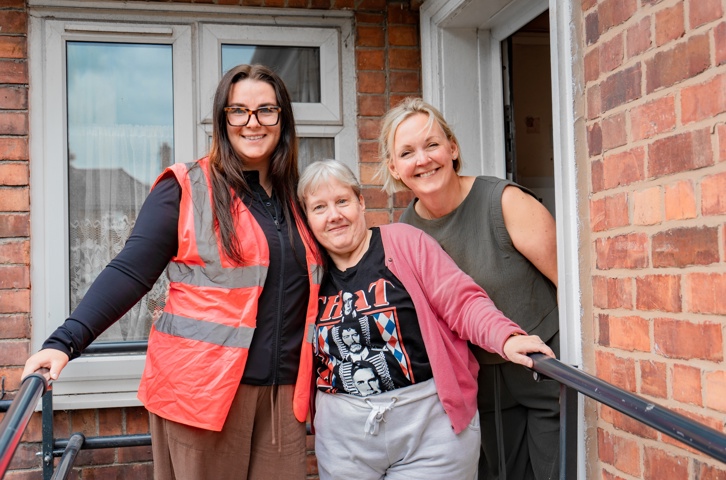 Two Magenta colleagues and a customer standing together outside a home.