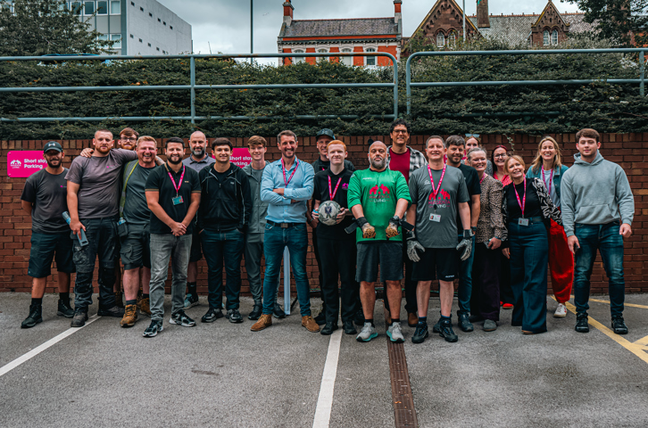Colleagues who took part in the ‘Beat the Keeper’ challenge at Magenta Living’s World Cup fundraising event gather for a group photo outdoors.